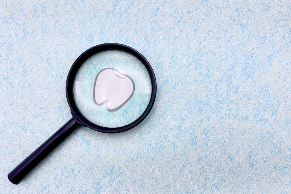 虫眼鏡で歯の絵を見ている画像