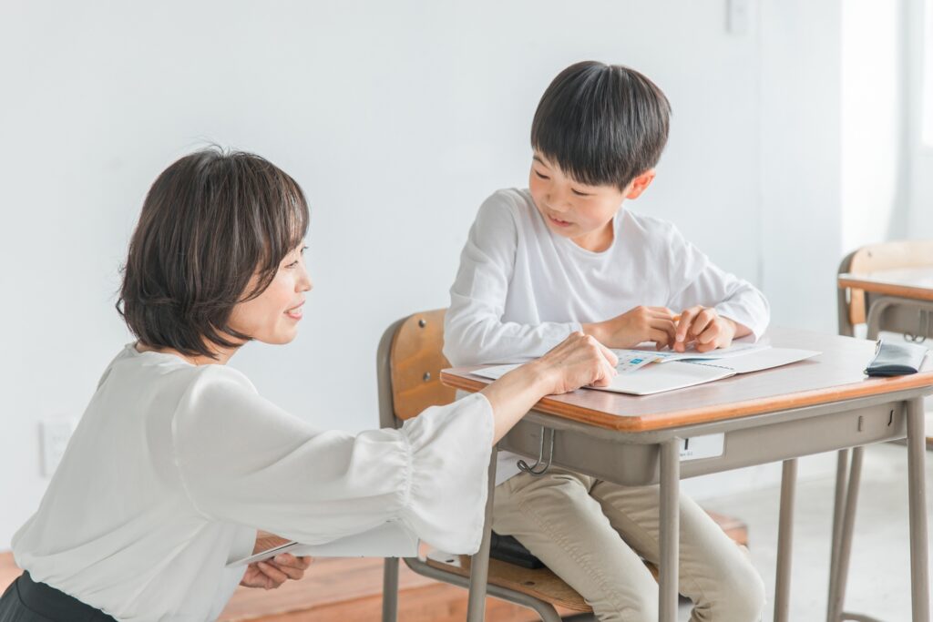 勉強する子供と指導する先生の画像