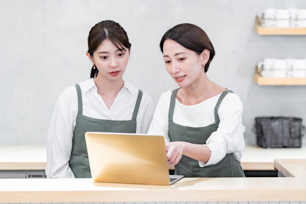 カフェ店員2人がパソコンで会議をしている様子の画像