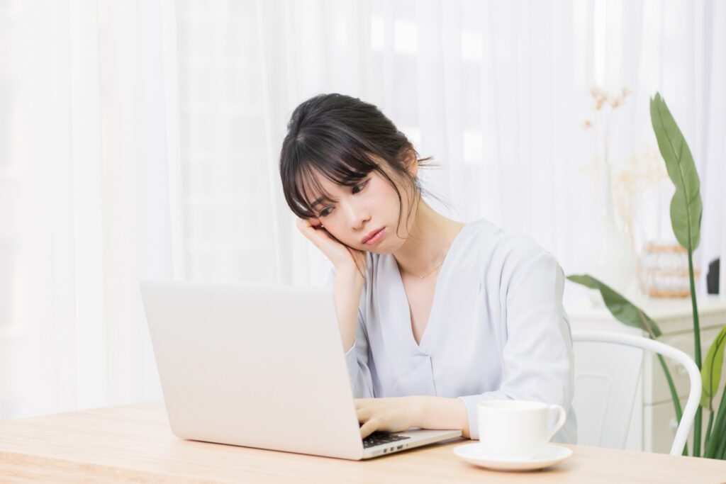 パソコンの前で悩んでいる女性の画像