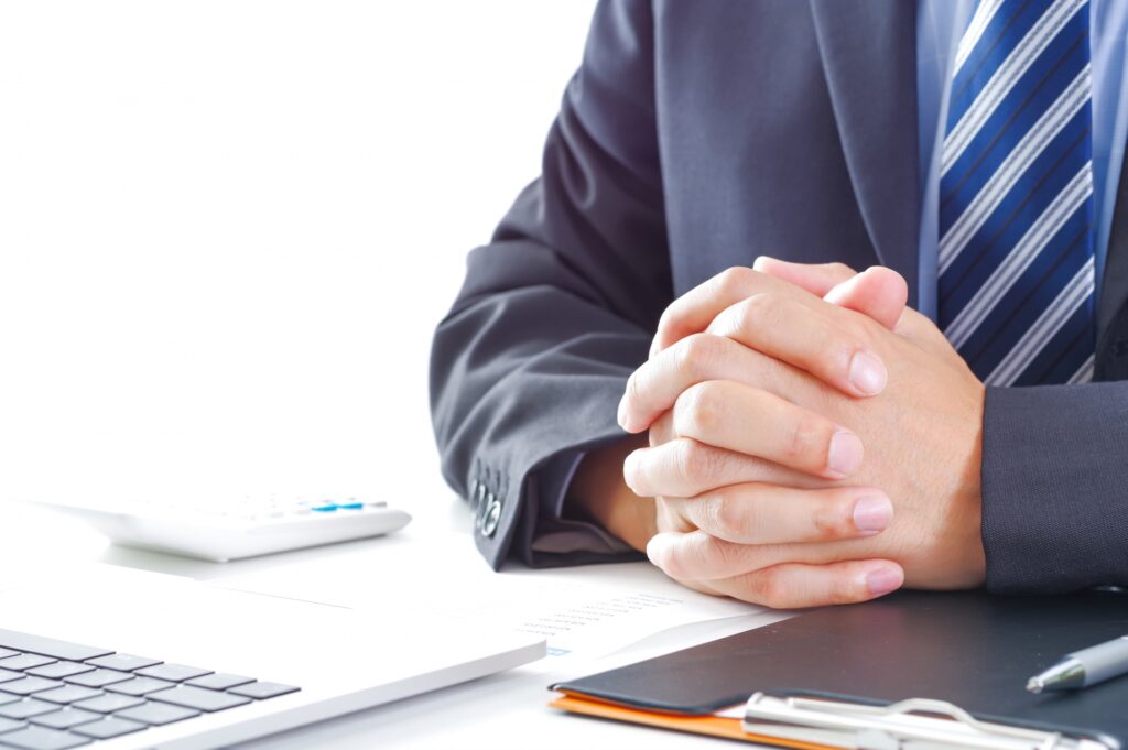 パソコンの前に座るスーツ姿の男性の画像