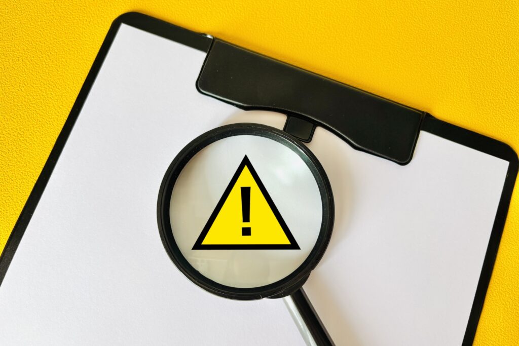 虫眼鏡と注意マークの画像