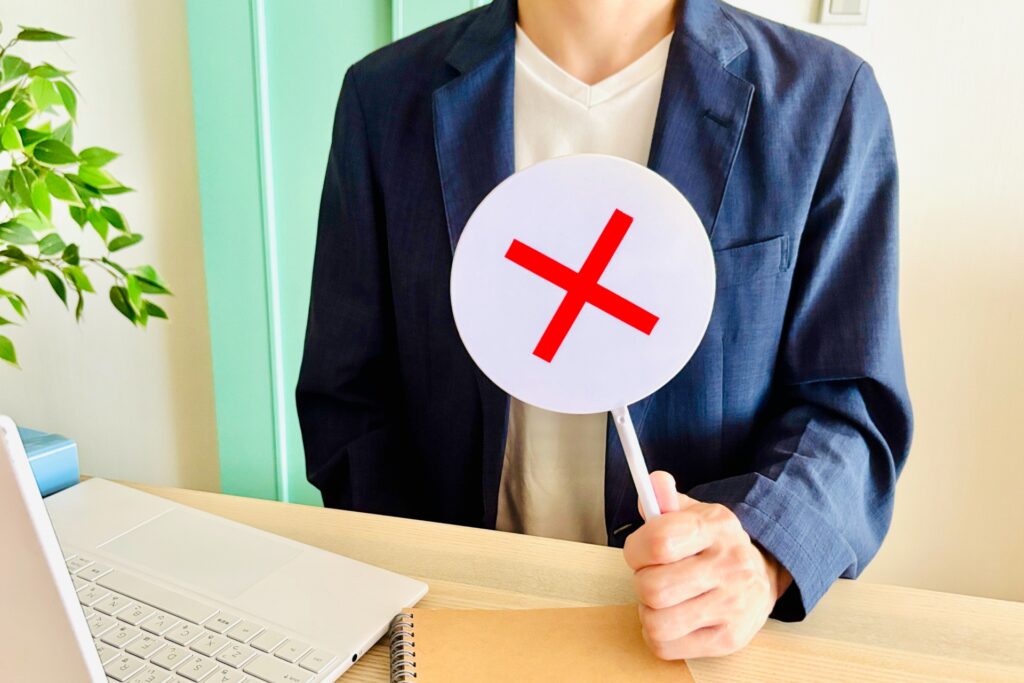 バツマークのプラカードを出す男性の画像