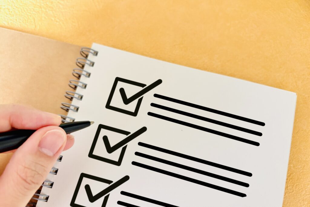 チェックリストに書き込む人の手の画像