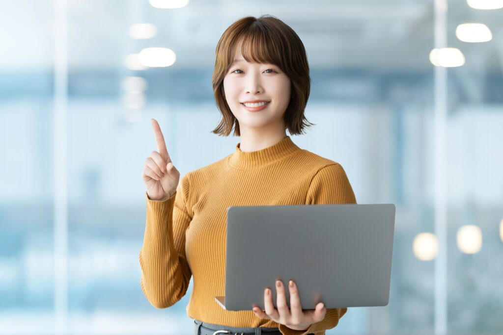 パソコンを持って案内をする笑顔の女性の画像