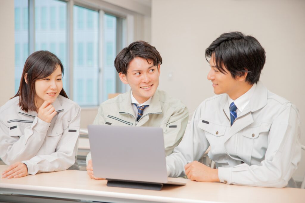 作業着を着てミーティングをする会社員の画像