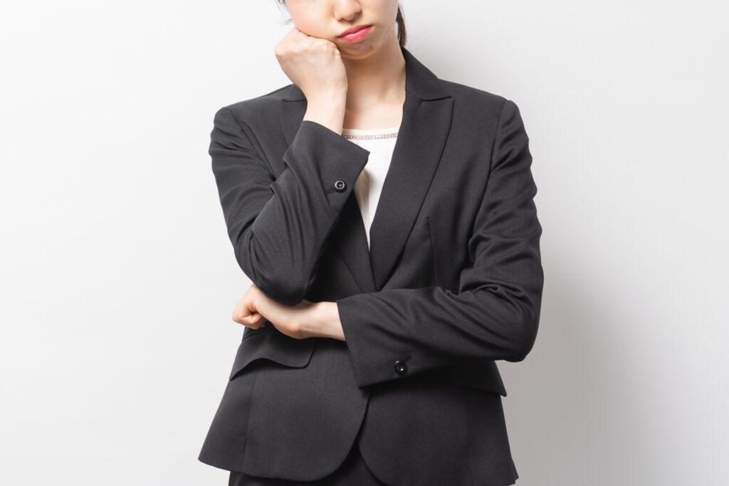 悩んでいるスーツの女性の画像